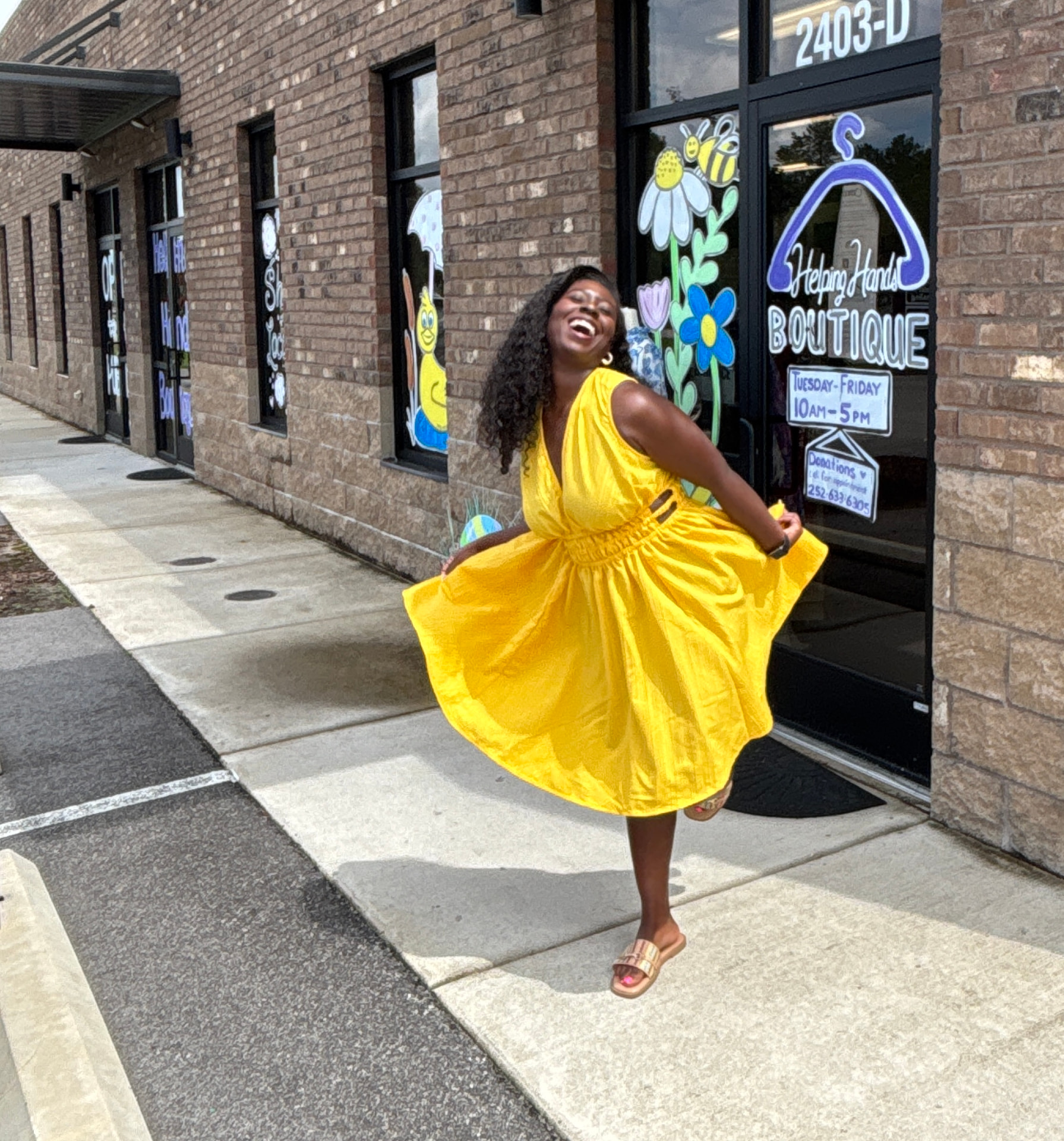 Moriah Davis twirling in a yellow dress outside Helping Hands Boutique