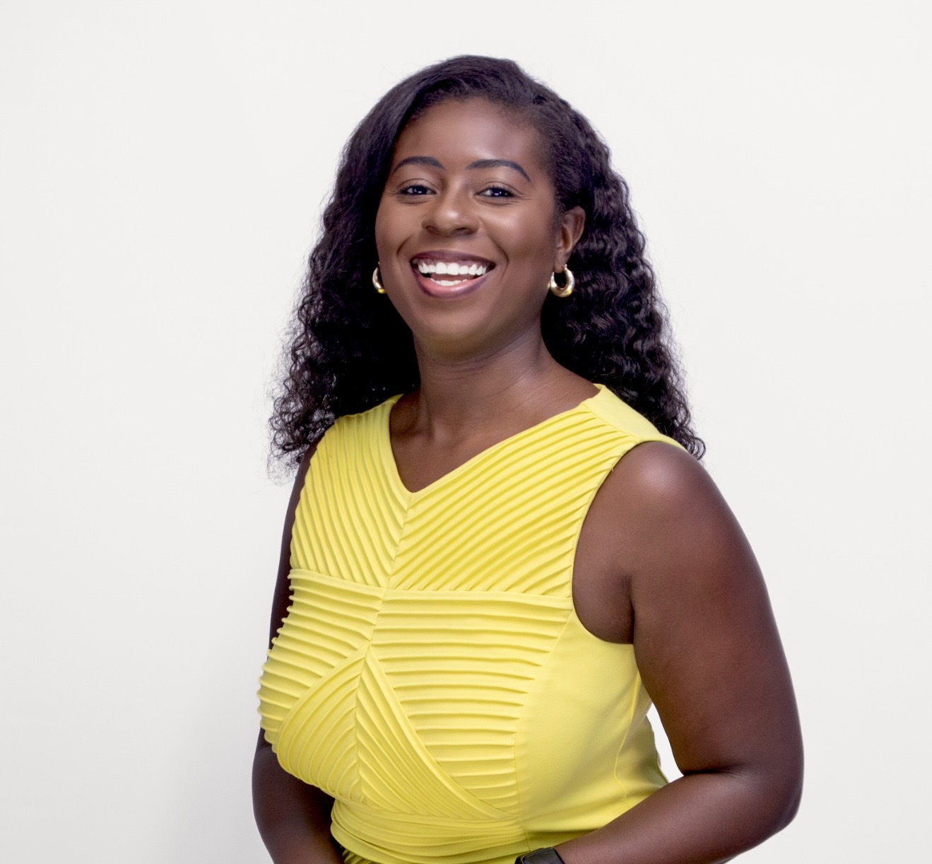 Moriah Davis smiling in a bright yellow dress against a soft studio background